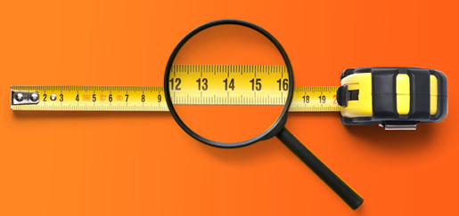 Magnifying glass examining a measuring tape on orange background